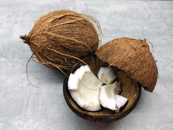 A mature brown coconut cracked open to show the firm white meat
